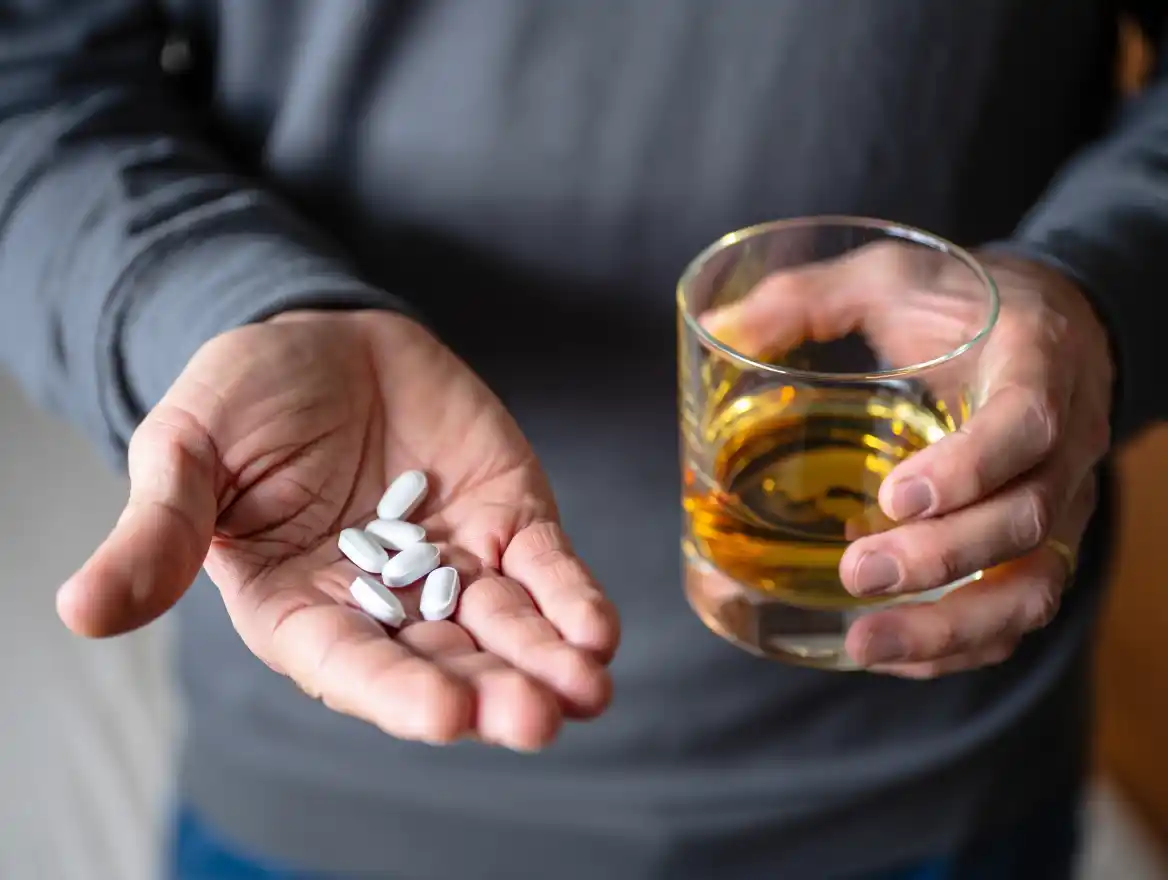 Мужчина держит алкоголь в одной рук и урсосан в другой